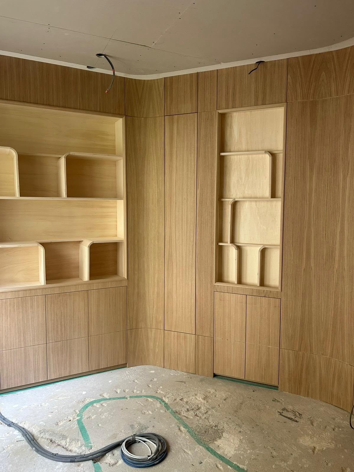 Boiserie en placage bois clair suivant la courbe du mur, niches à casiers aux angles arrondis