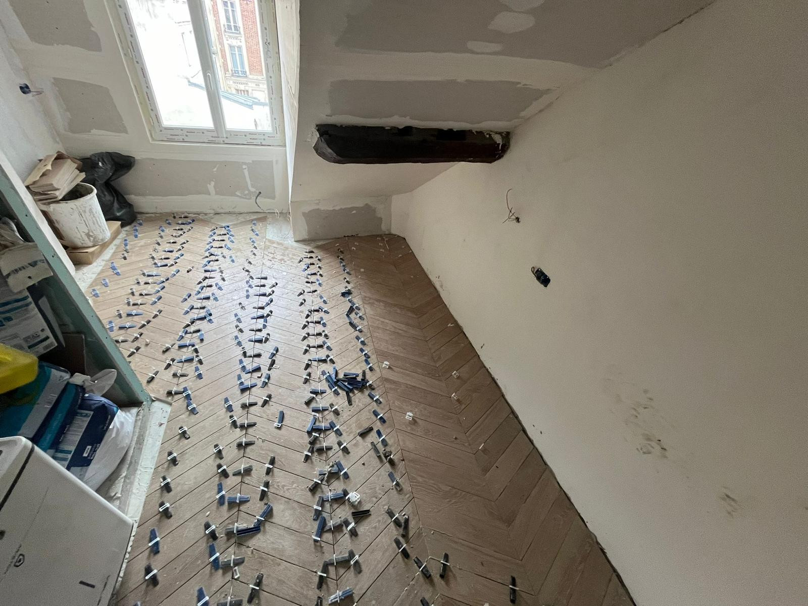 Carrelage effet bois en cours de pose en bâtons rompus, croisillons autonivelants encore en place