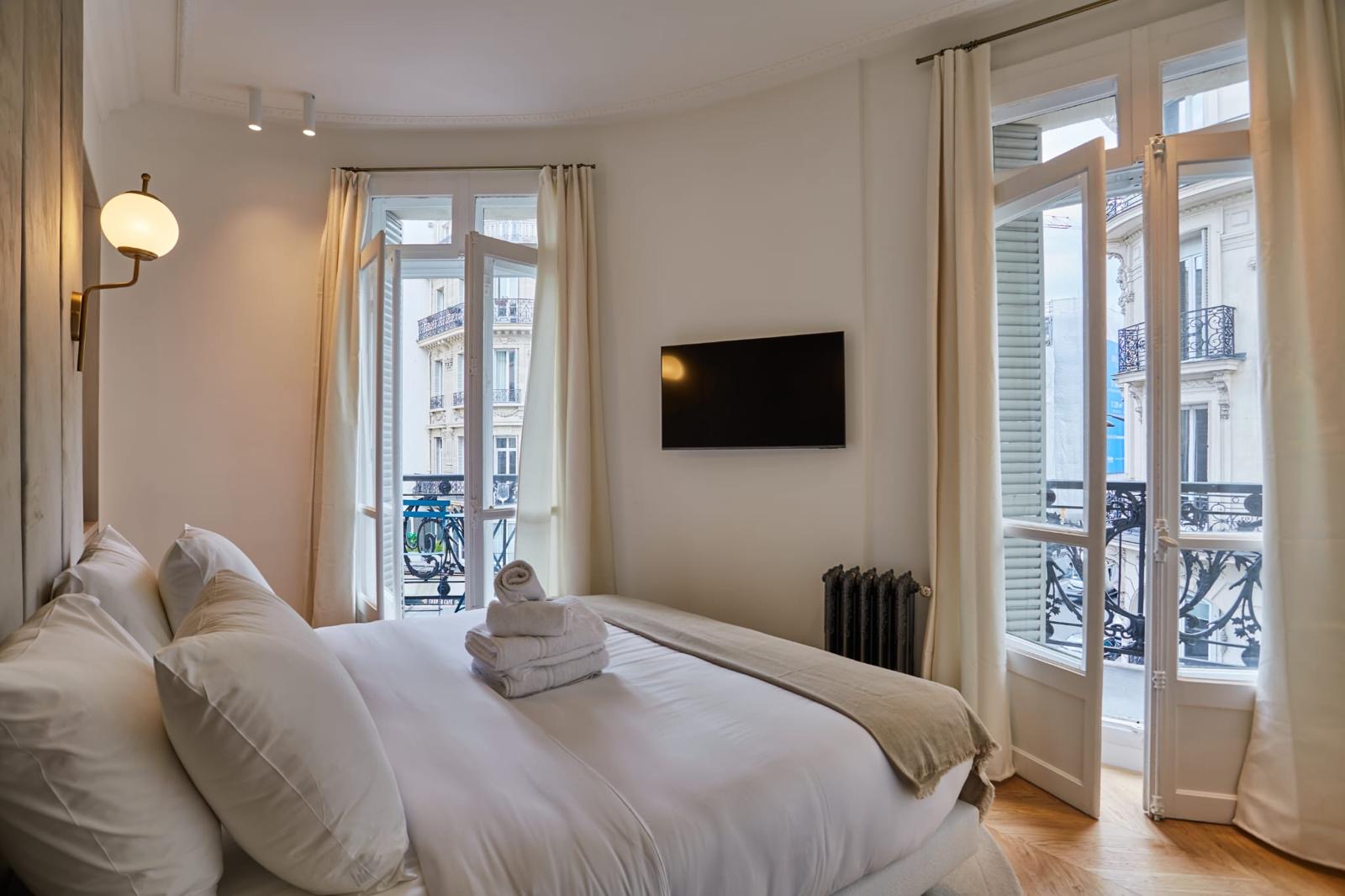 Chambre d'angle à mur arrondi, deux portes-fenêtres sur balcons à garde-corps en fonte