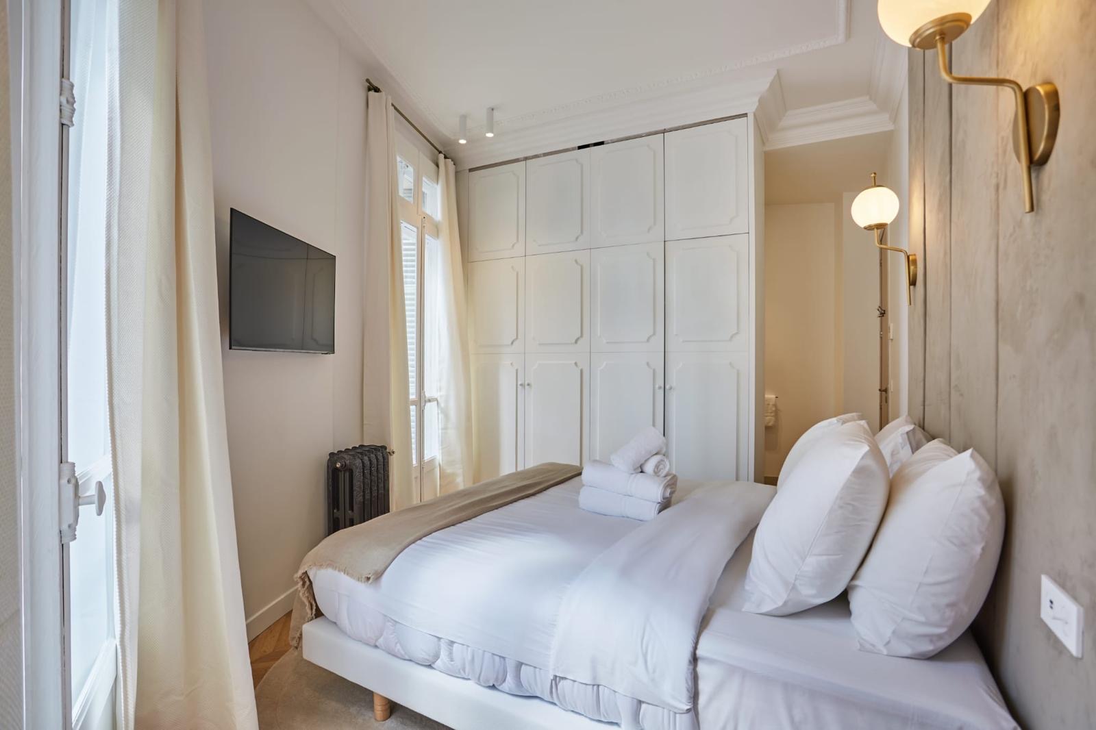 Chambre rénovée avec placard toute hauteur dont les façades reprennent les panneaux moulurés de la pièce