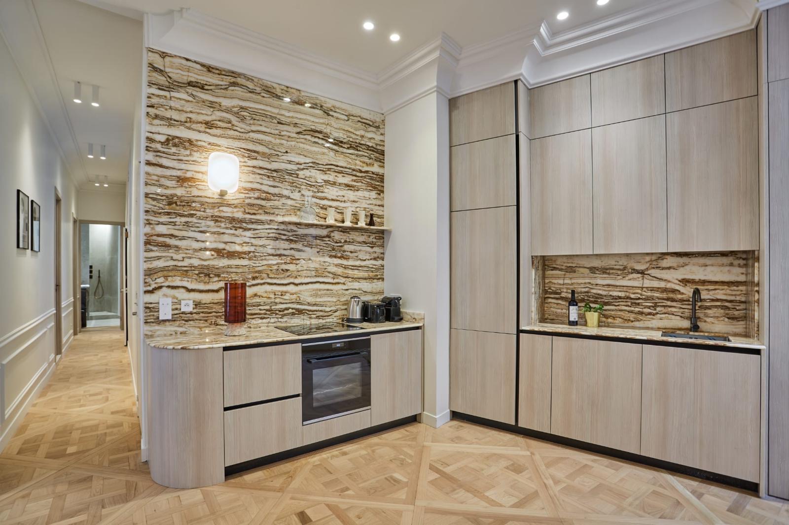 Réalisation de rénovation d'appartement : cuisine en placage bois clair, parement en pierre naturelle rubanée et parquet chêne en panneaux de Versailles