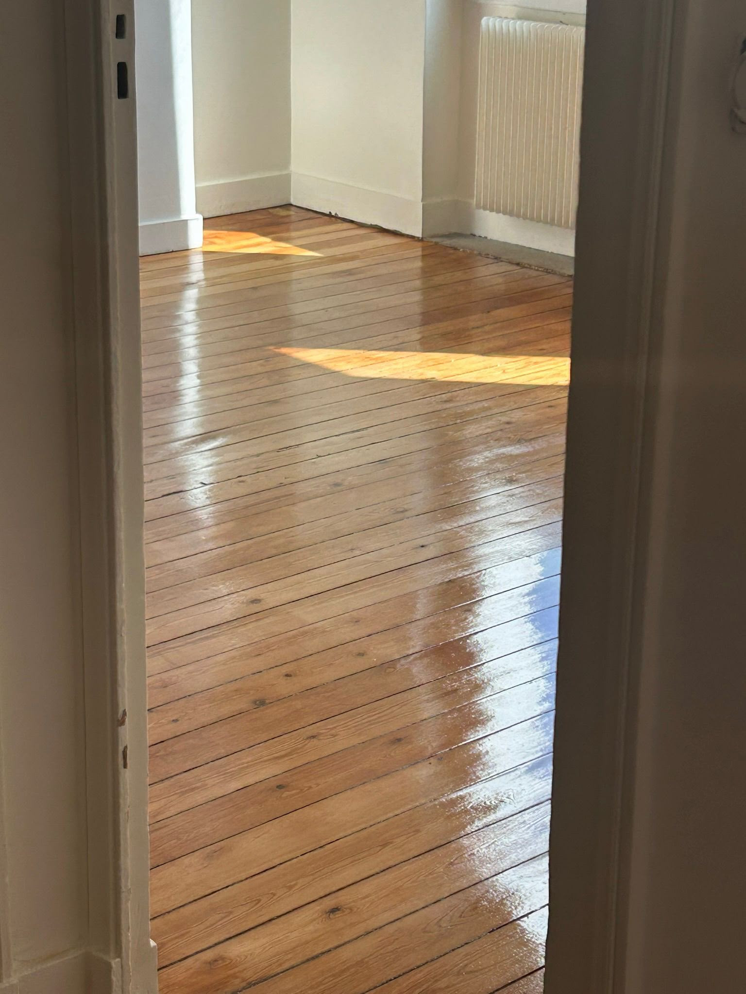 Parquet ancien à larges lames poncé et vitrifié, radiateur à colonnes conservé