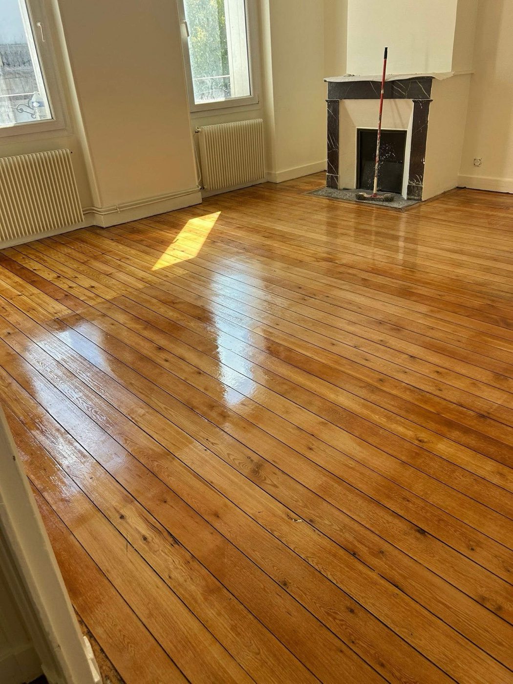 Ancien parquet à lames droites, poncé puis vitrifié, cheminée d'origine conservée. Chantier réel des équipes partenaires.