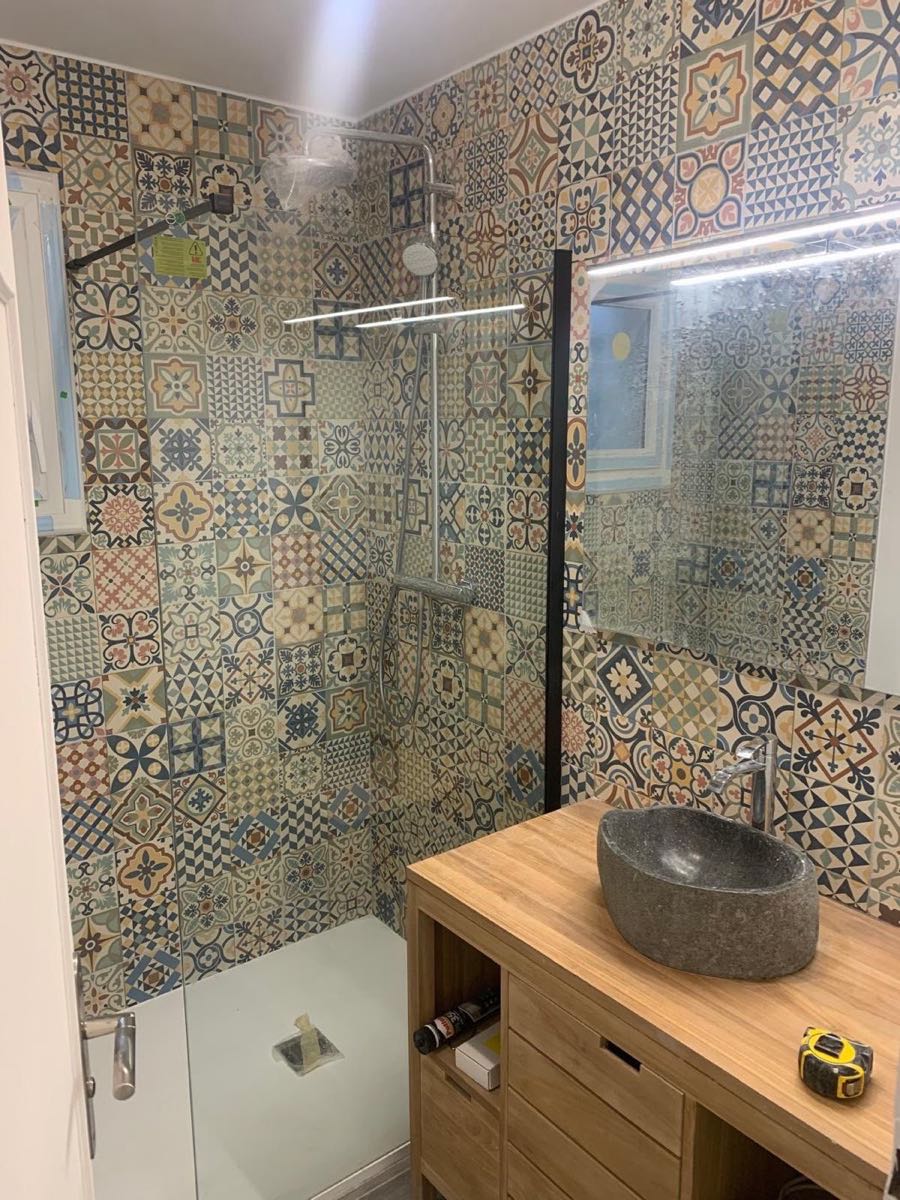Douche en carreaux de ciment : sur les parois, un joint entre chaque carreau — soit un linéaire de joints considérable en zone d'eau. Le receveur, lui, est un bac d'une seule pièce. Chantier réel des équipes partenaires.