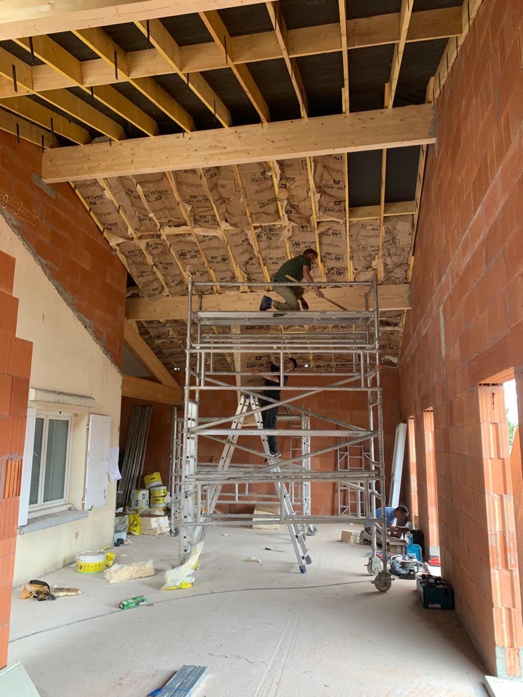Élévation en briques monomur, plancher bois de l'étage posé et isolation de rampant en cours. Chantier réel des équipes partenaires.