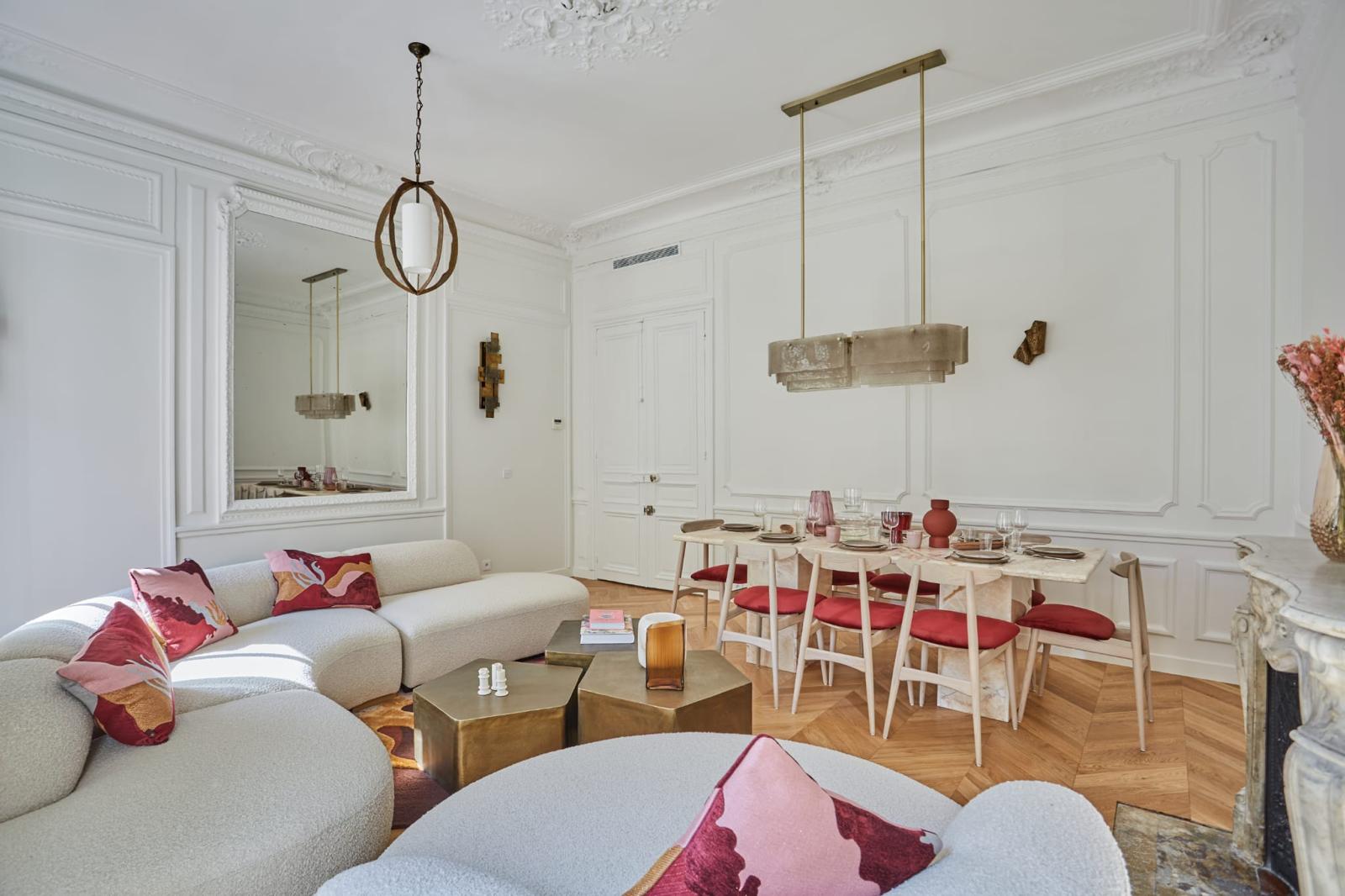 Salon et salle à manger d'un appartement haussmannien rénové à Paris : moulures, miroir encadré, parquet chêne en point de Hongrie